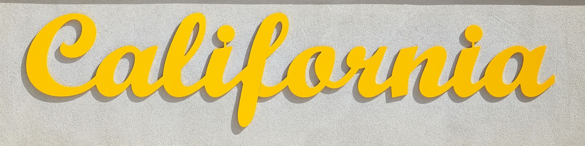 The image shows the word "California" in yellow cursive lettering against a light gray textured background.