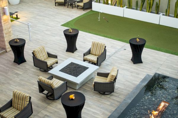 The image shows an outdoor patio with wicker chairs, a fire pit, tall tables, and a rectangular pool. A sign reads "California."