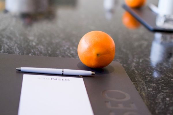 The image shows a table set with notepads, pens, and oranges, possibly in a meeting or conference setting.