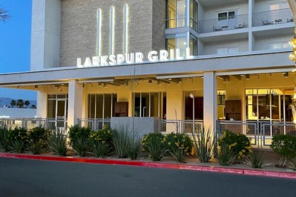 The image shows the exterior of Larkspur Grill, a modern building with illuminated signage and landscaping in front of it.