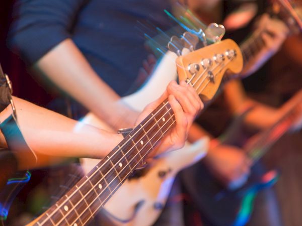 The image shows blurred motion of musicians playing electric guitars, capturing dynamic movement and energy during a live performance.