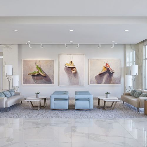 A modern lobby with sleek furniture, large artworks on the wall, soft lighting, and a glossy marble floor, creating a welcoming atmosphere.